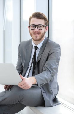 Genç profesyonel ofis pencere arka plan üzerinde dizüstü bilgisayar ile