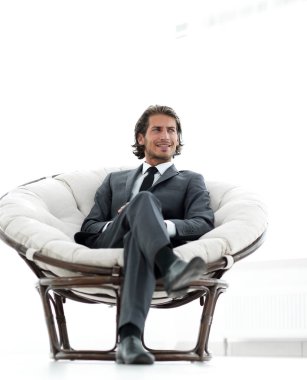 Kendine güvenen işadamı büyük bir rahat sandalyede oturuyor.