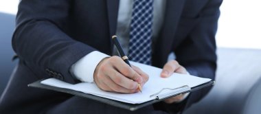 İşadamı bir sözleşme imzalar. Elinde kalem tutan.