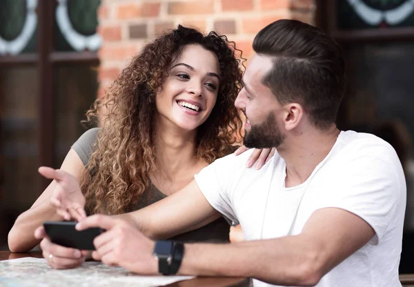 Happy älskande par som med en smartphone som sitter i terrass — Stockfoto