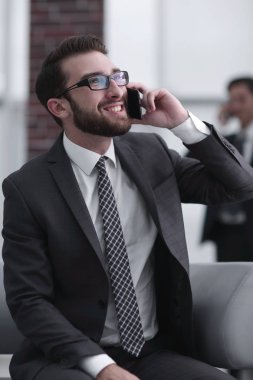 Modern bir binada telefonda konuşan çekici bir işadamı.