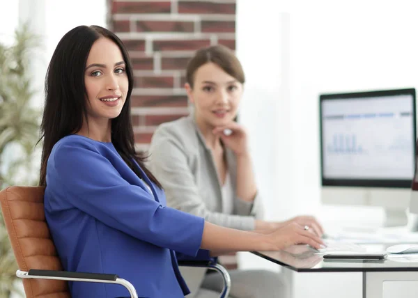 young woman looking at camera and smiling sitting at workplace