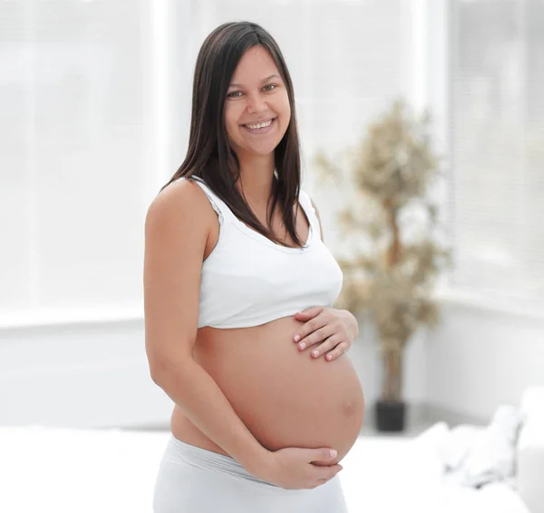 Portrait of young pregnant woman on a light background. — Stock Photo, Image