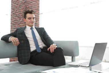 Genç işadamı ofiste dizüstü bilgisayarla çalışıyor.