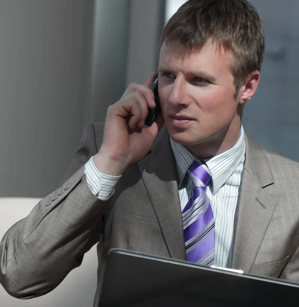 Aantrekkelijke Europese man praten over de telefoon terwijl het gebruiken van laptop. — Stockfoto