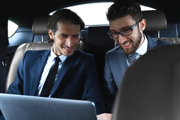 Two businessman talking while sitting in the car — Stock Photo, Image