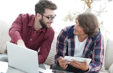 dizüstü ve tablet kanepede oturan çalışan iki genç adam