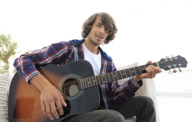 adam bir şarkı söyler ve kanepede oturan gitar çalar.