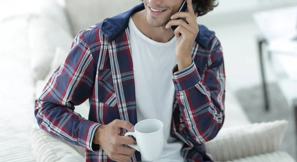 Vacker kille med en kopp sitter framför en bärbar dator. — Stockfoto