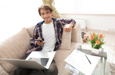 dizüstü bilgisayar ve oturma odasında kanepede oturan smartphone başarılı adam