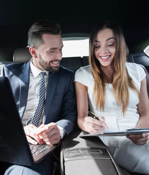 Man en vrouw bespreken werkdocumenten in taxi — Stockfoto
