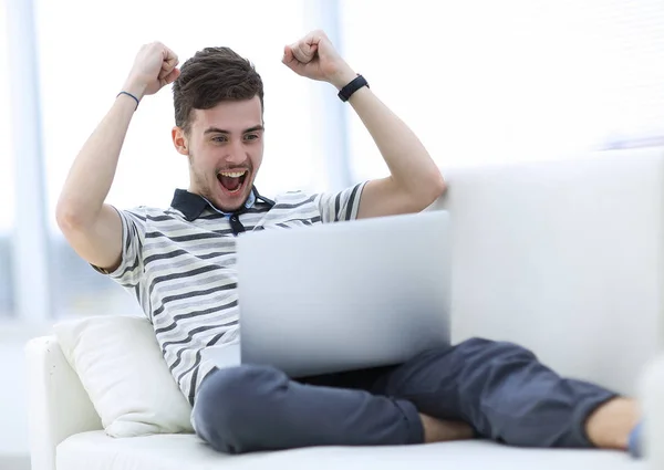 Hombre feliz con el ordenador portátil sentado en el sofá — Foto de Stock