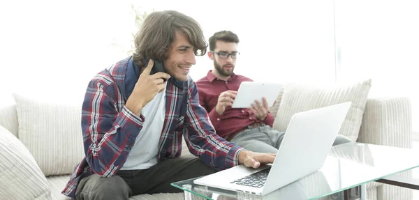 2 人の男がソファに座って、携帯電話で話している、インターネット上のチャット. — ストック写真