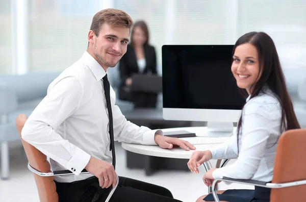 members of the business team sitting at Desk and looking at camera .