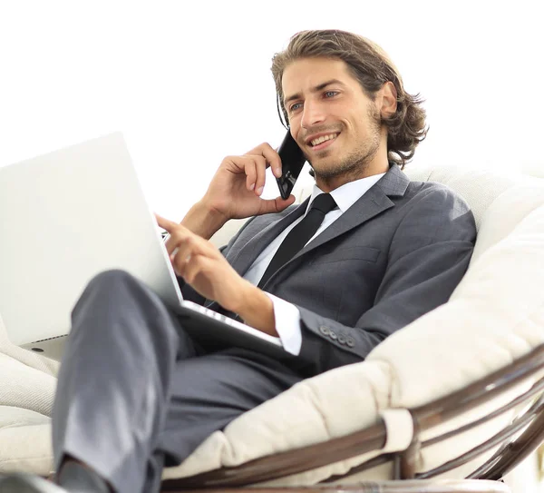 onun evinde sandalyede oturan smartphone cep telefonu ile konuşurken işadamı