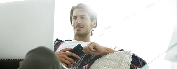 Photo jeune homme avec smartphone assis sur une chaise. sur un fond flou — Photo