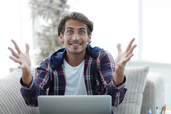 Szczęśliwy udanych młody człowiek ogląda laptopa w domu. — Zdjęcie stockowe