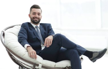 Kendine güvenen işadamı bir sandalyede oturuyor