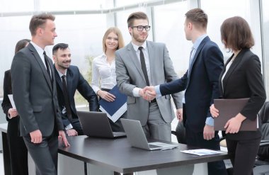 Ofisteki bir toplantıda iş ortakları tokalaşıyor.