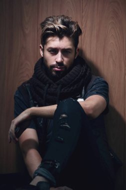 Sıradan giyinmiş sakallı bir adam oturur.