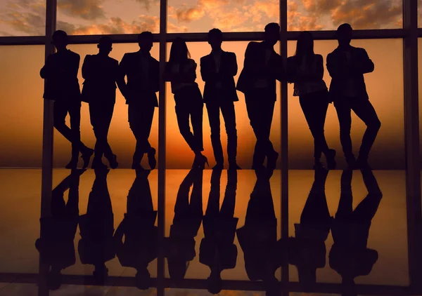 Silhouette of a business team standing next to the office window — Stock Photo, Image