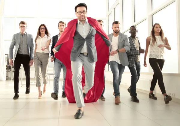 Homme d'affaires dans un manteau de superhéros est en avance sur l'équipe d'affaires — Photo