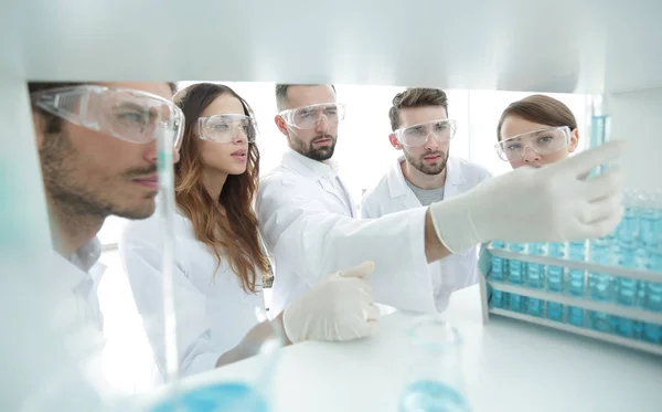 Image de fond est un groupe de microbiologistes étudiant le liquide dans le tube de verre . — Photo