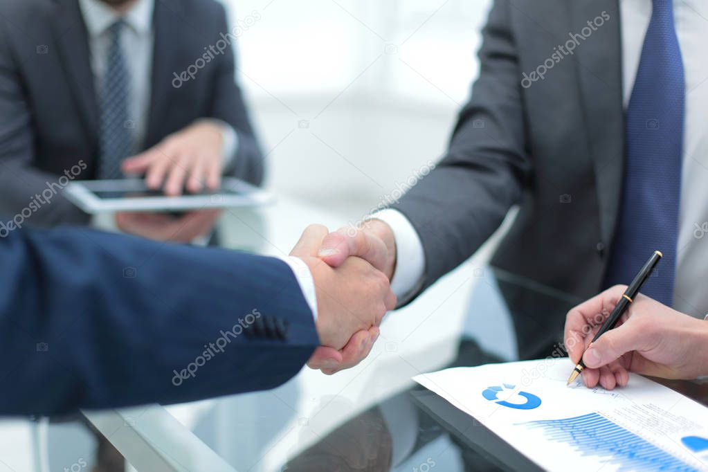 Men shaking hands with smile at office with their coworkers.