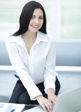 bulanık bir arka plan üzerinde bir masada oturan başarılı genç kadın.