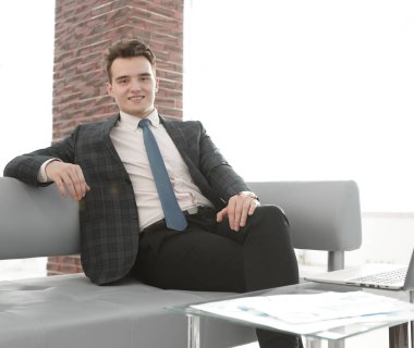 Genç işadamı ofiste dizüstü bilgisayarla çalışıyor.