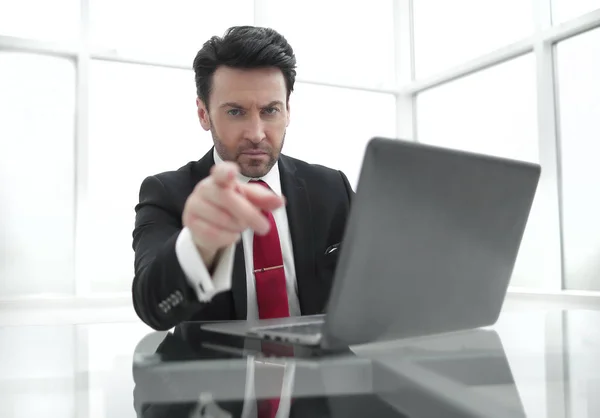 Komoly üzletember, rámutatva az ujját magad, az íróasztalánál ül — Stock Fotó