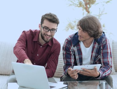 dizüstü ve tablet kanepede oturan çalışan iki genç adam