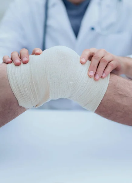 Traumatologue, appliquant un bandage sur le genou — Photo