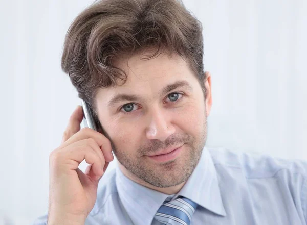 Hombre de negocios guapo sentado en el escritorio y hablando en un teléfono celular —  Fotos de Stock