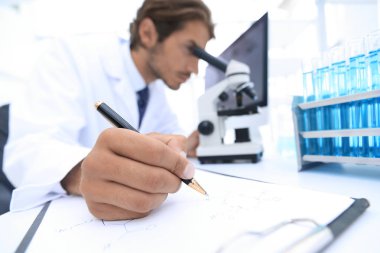 Bilimadamı laboratuarda bir deney notu yazar.