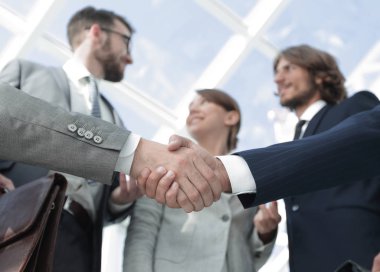 İş ortaklarının el sıkışması ön planda.