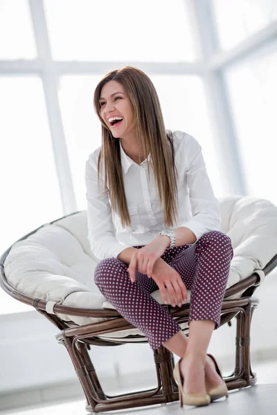 Jonge vrouw zitten in de comfortabele stoel lachen — Stockfoto