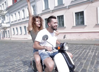 mutlu genç bir çift bir scooter üzerinde eğleniyor