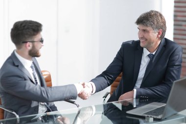 Toplantı sırasında iki iş arkadaşı el sıkışıyor.