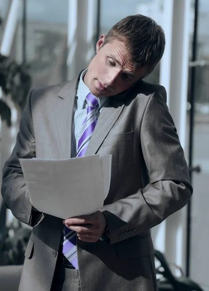 Attraktiver junger Geschäftsmann schaut beim Reden auf Dokument — Stockfoto