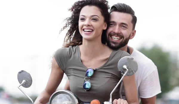 Attractive couple riding a scooter on a sunny day in the city — Stock Photo, Image