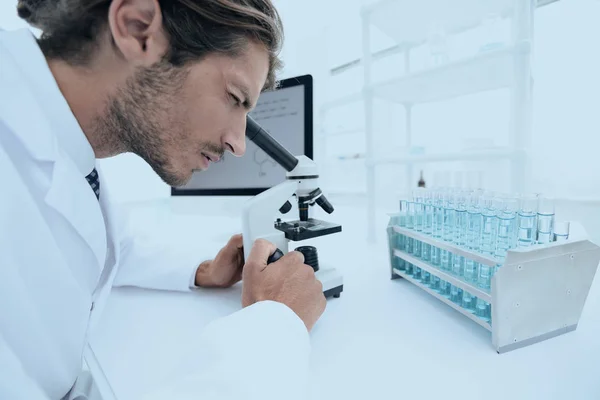 Científico de laboratorio joven mirando el microscopio en el laboratorio — Foto de Stock