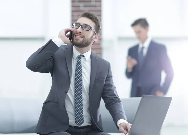 Confident young man talking on phone in office — Stock Photo, Image