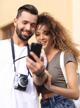 Mutlu genç çift cep telefonuyla yer arıyor.