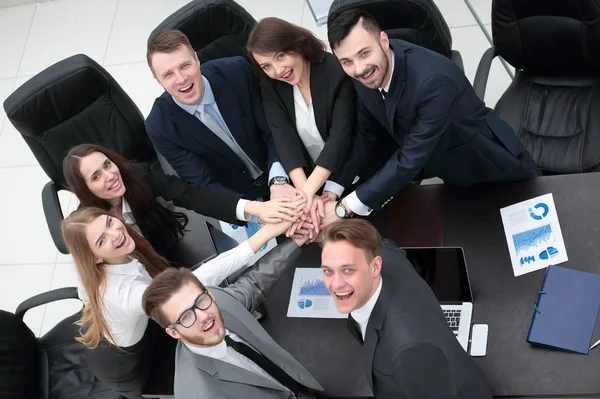 Equipo de negocios con las manos juntas en el escritorio — Foto de Stock