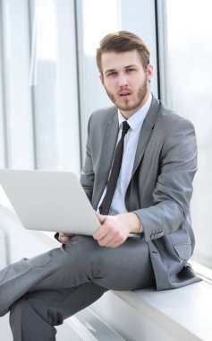 Genç profesyonel ofis pencere arka plan üzerinde dizüstü bilgisayar ile