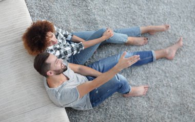 yeni bir oturma odasında bir halı üzerinde oturan yeni evli çift