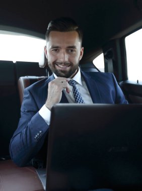 Bir arabanın arka koltuğunda oturan başarılı adam