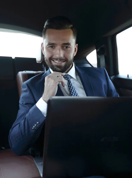 successful man sitting in the back seat of a car