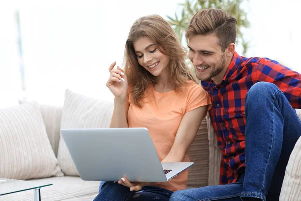 Mladý muž se svou přítelkyní, sledovat televizní pořad na notebooku, sedí v obývacím pokoji — Stock fotografie